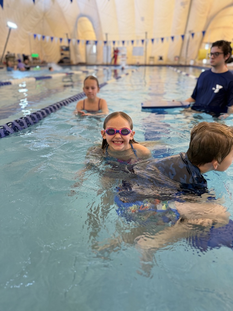 An instructor helps children learn to swim.