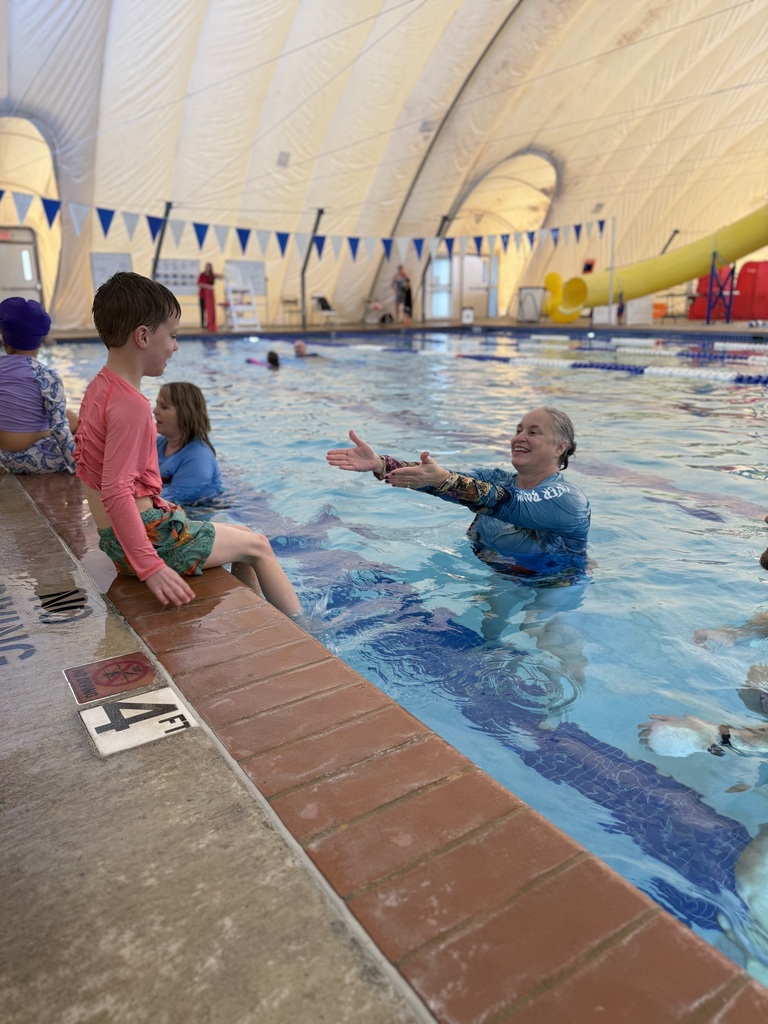 An instructor helps a child learn to swim.
