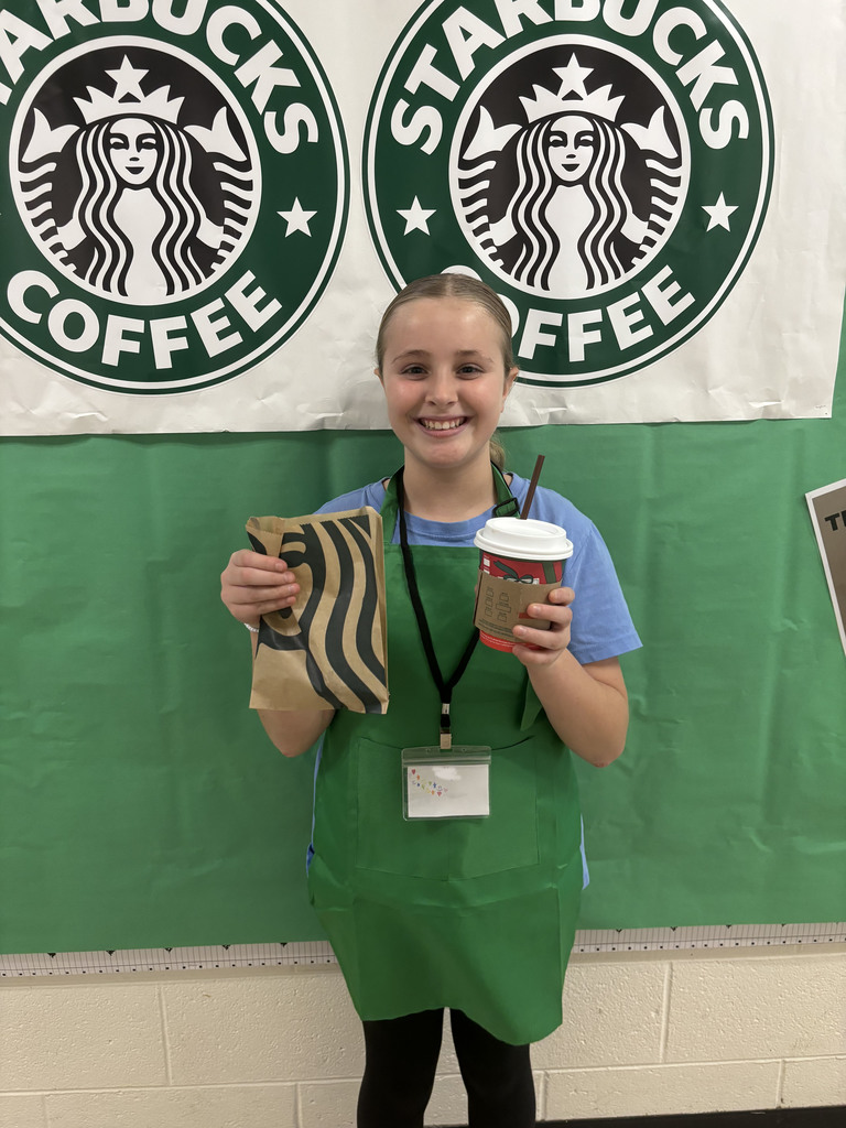 A student  poses for a photo in front of a Starbucks themed bulletin board.