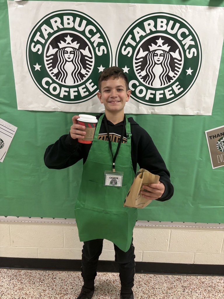 A student  poses for a photo in front of a Starbucks themed bulletin board.