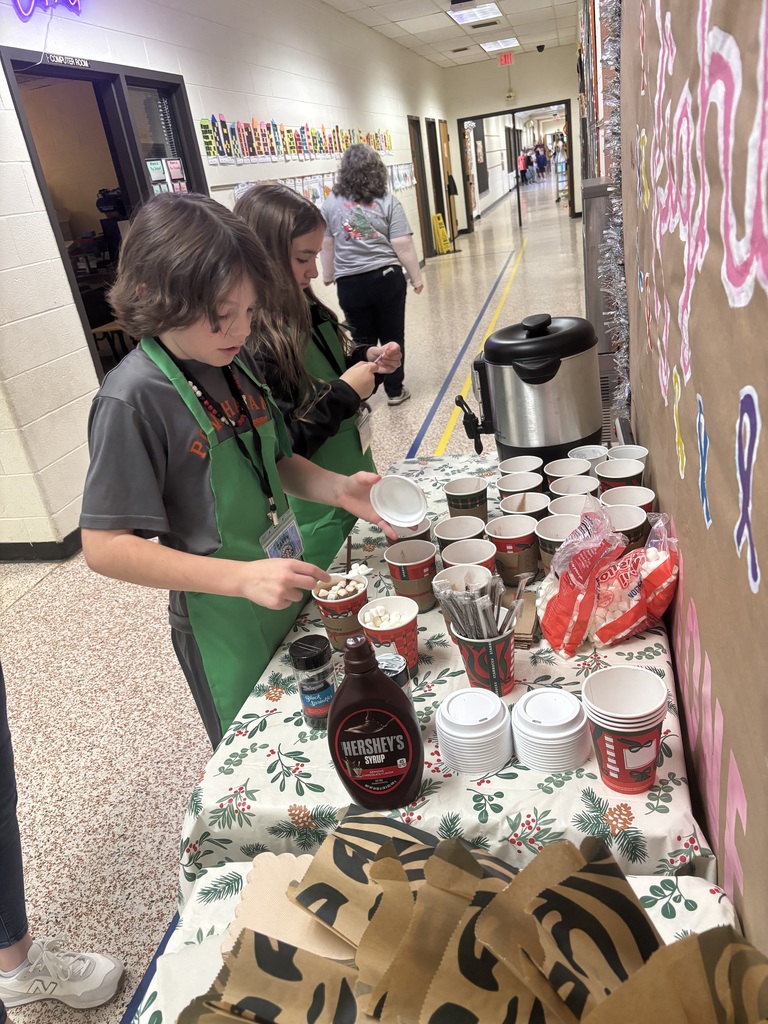 Students get hot chocolate at a table.