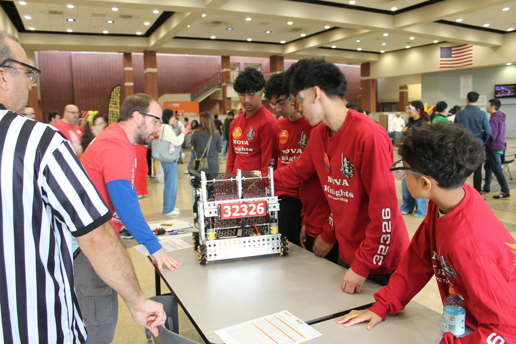 Volunteers help a visiting robotics team at a robotics competition.