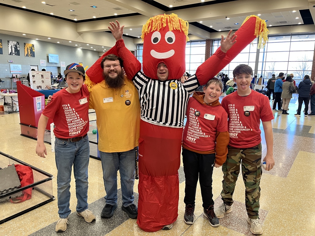 A person in a costume poses for a photo with four other people.