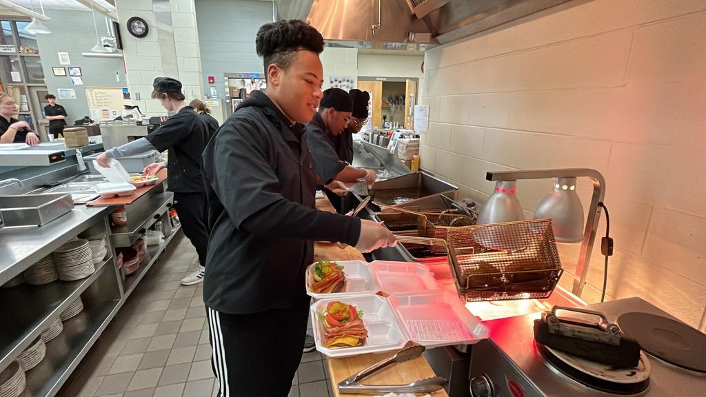 Culinary students in a kitchen cook lunch.