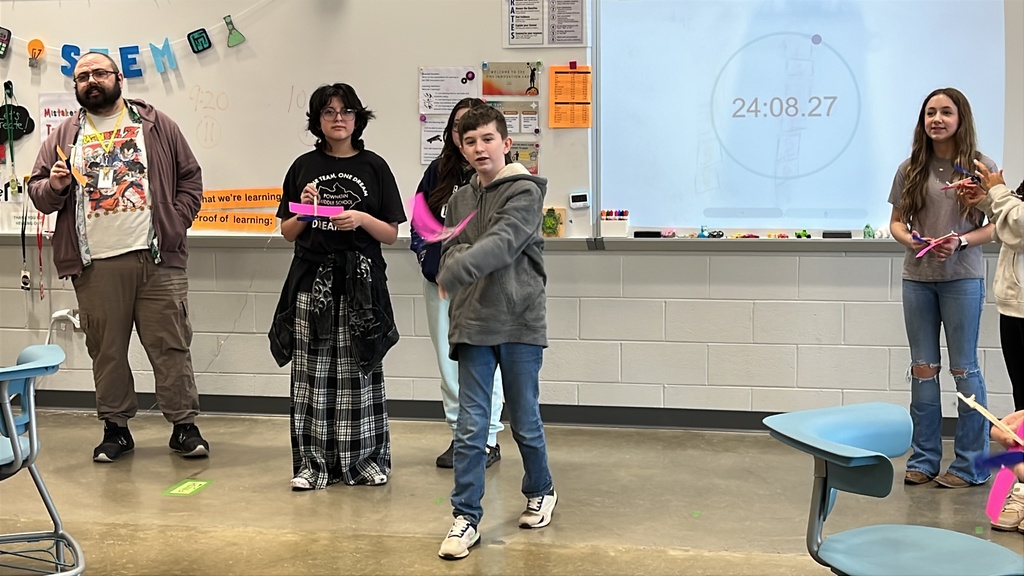 Students throw wind up airplanes their class made on an assembly line.