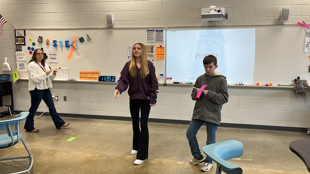 Students throw wind up airplanes their class made on an assembly line.
