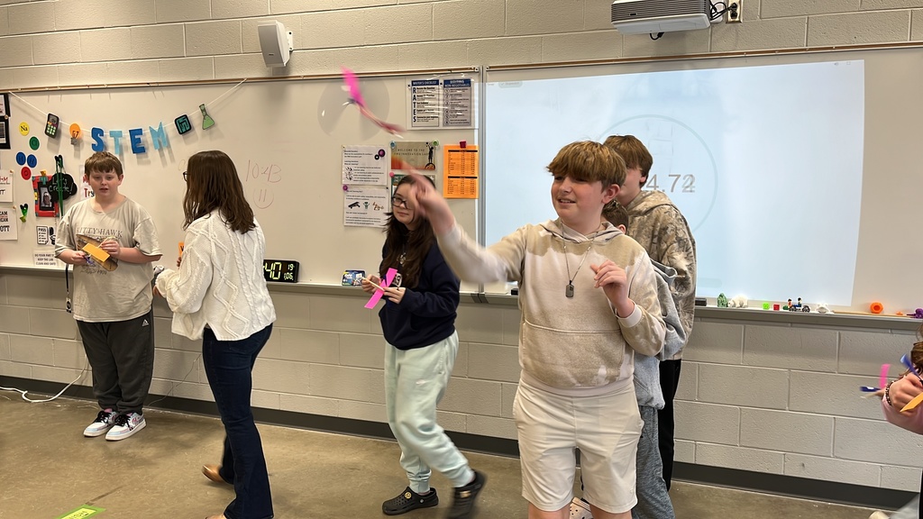 Students throw wind up airplanes their class made on an assembly line.