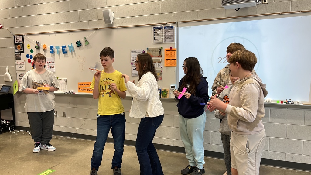 Students throw wind up airplanes their class made on an assembly line.