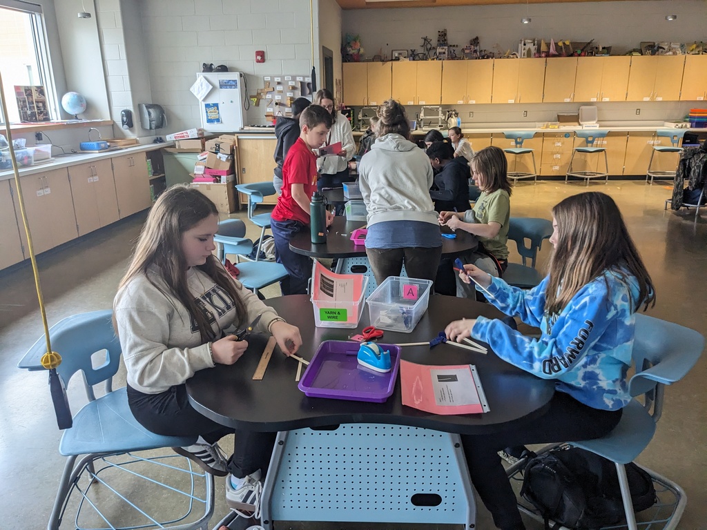 Students work on an assembly line making airplanes in class. 