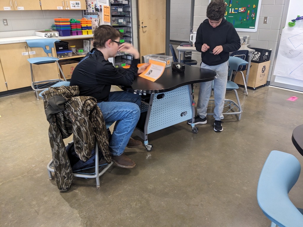 Students work on an assembly line making airplanes in class. 