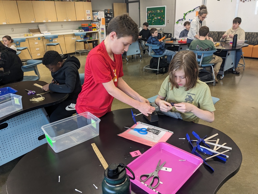 Students work on an assembly line making airplanes in class. 
