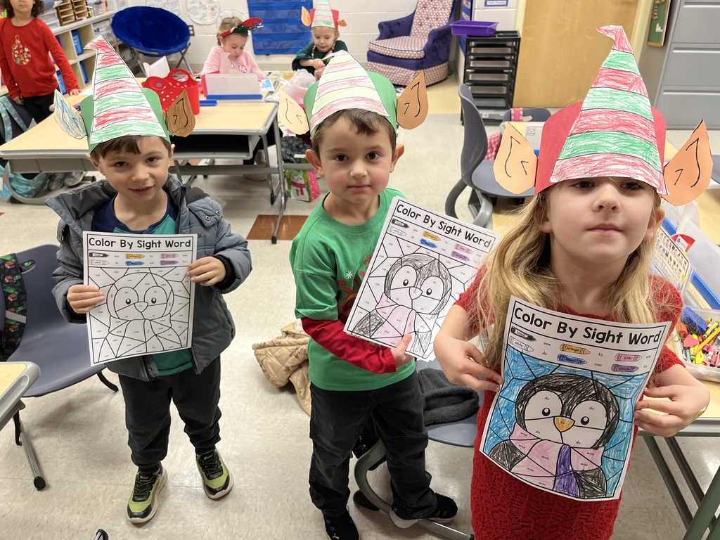 Students in elf hats  show off their coloring sheets.
