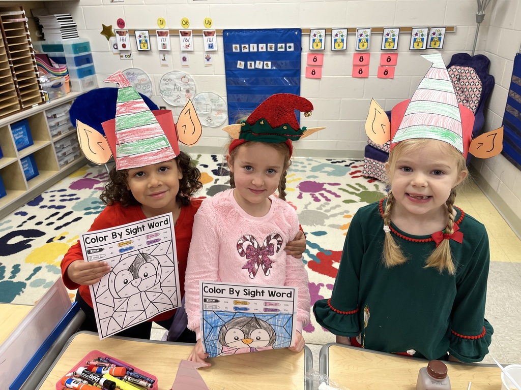 Students in elf hats  show off their coloring sheets.