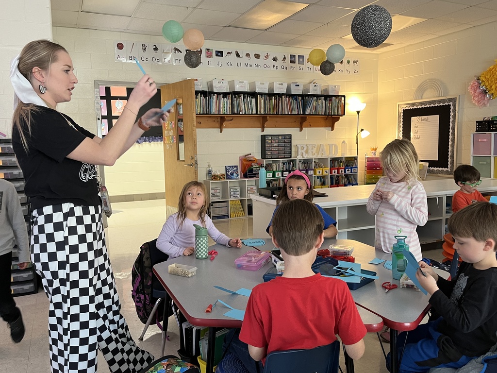 First graders work on a sun tracker in class. A teacher instructs them.