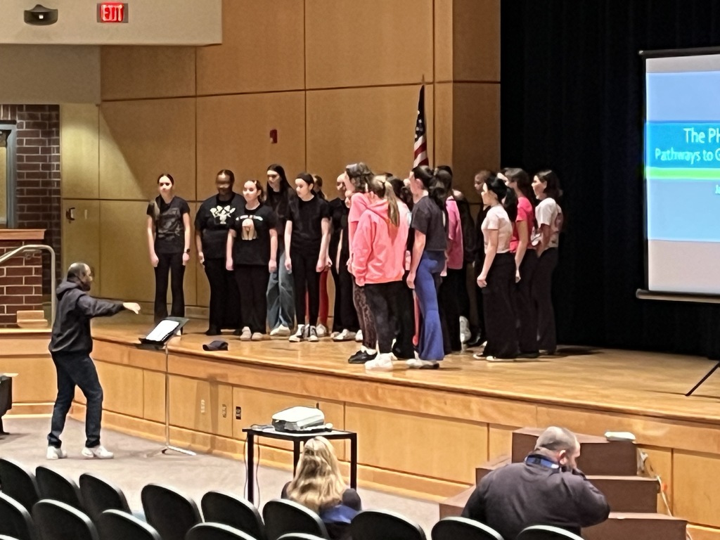 A chorus group performs for parents and students at a high school information night.