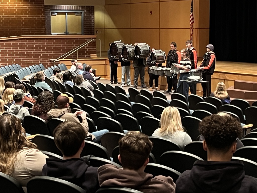 A drumline group performs for parents and students at a high school information night.