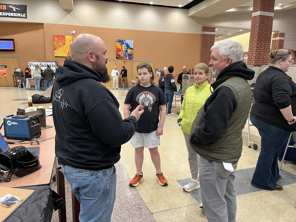 A family visits a booth at a high school information night.