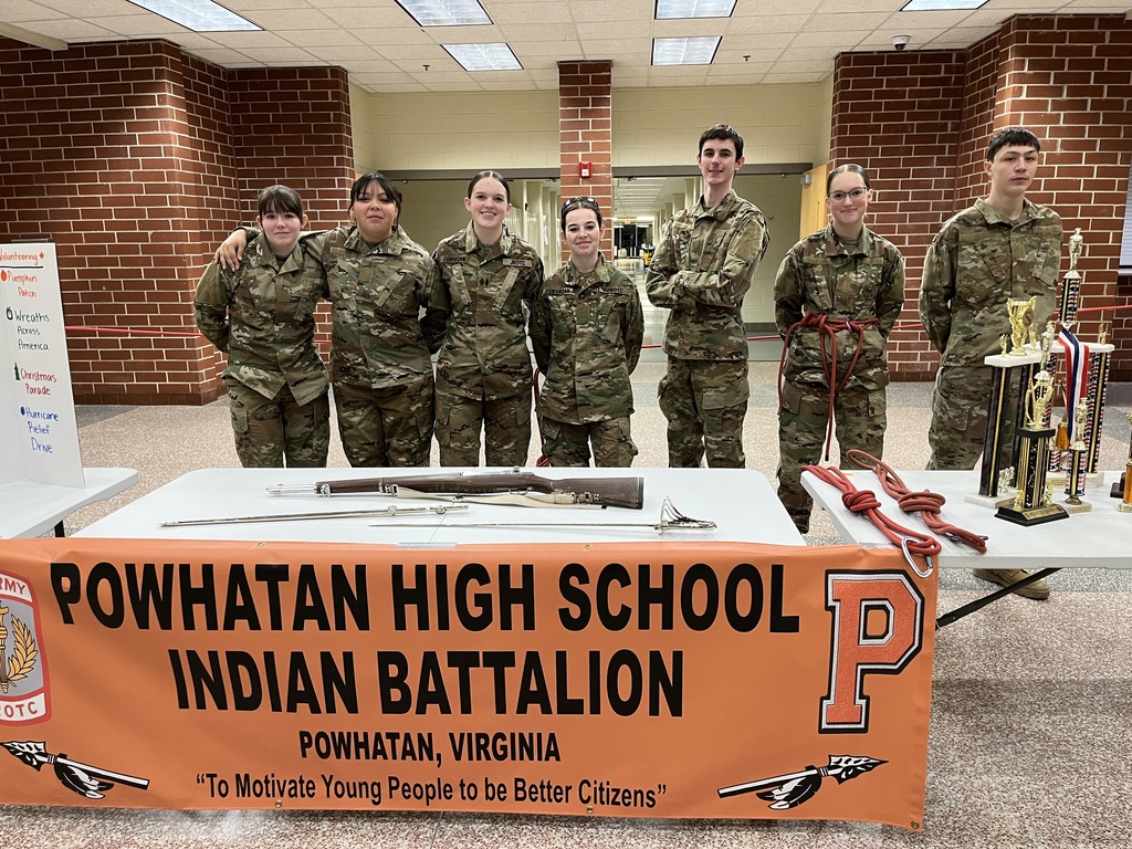 Cadets pose at a booth at a high school information night.
