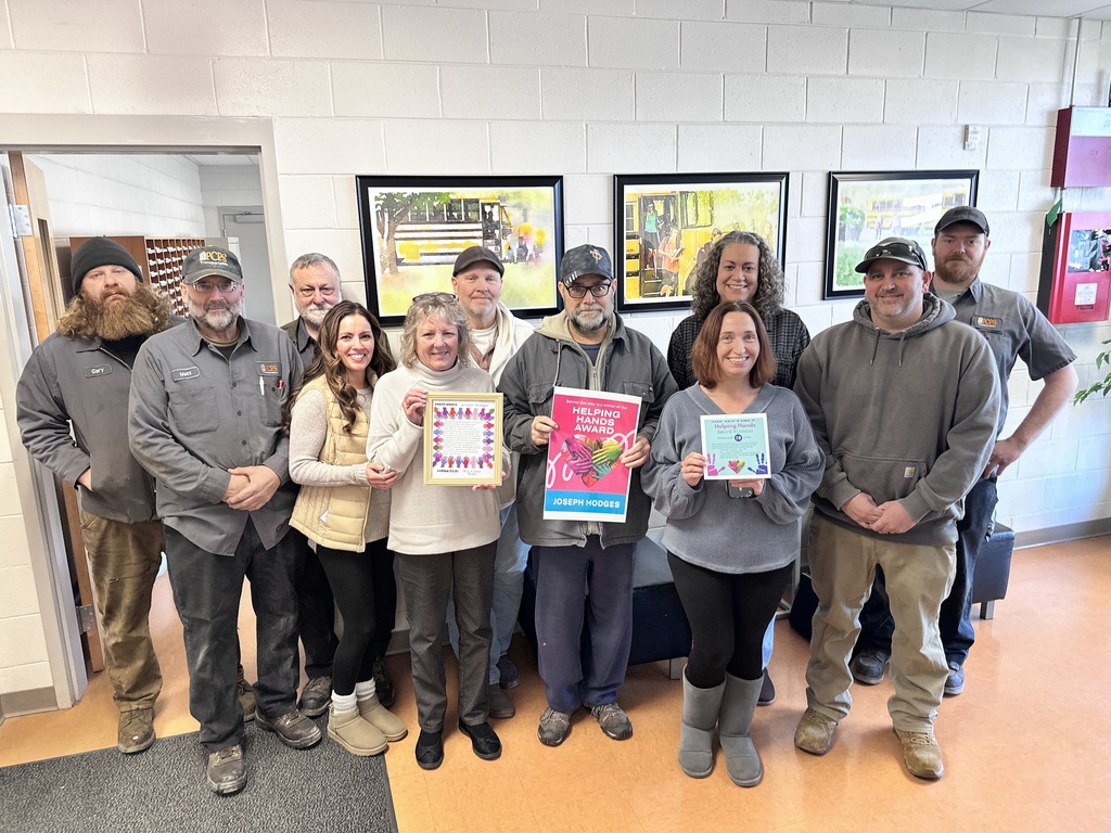 A group of men and women pose for a photo. Some hold certificates.