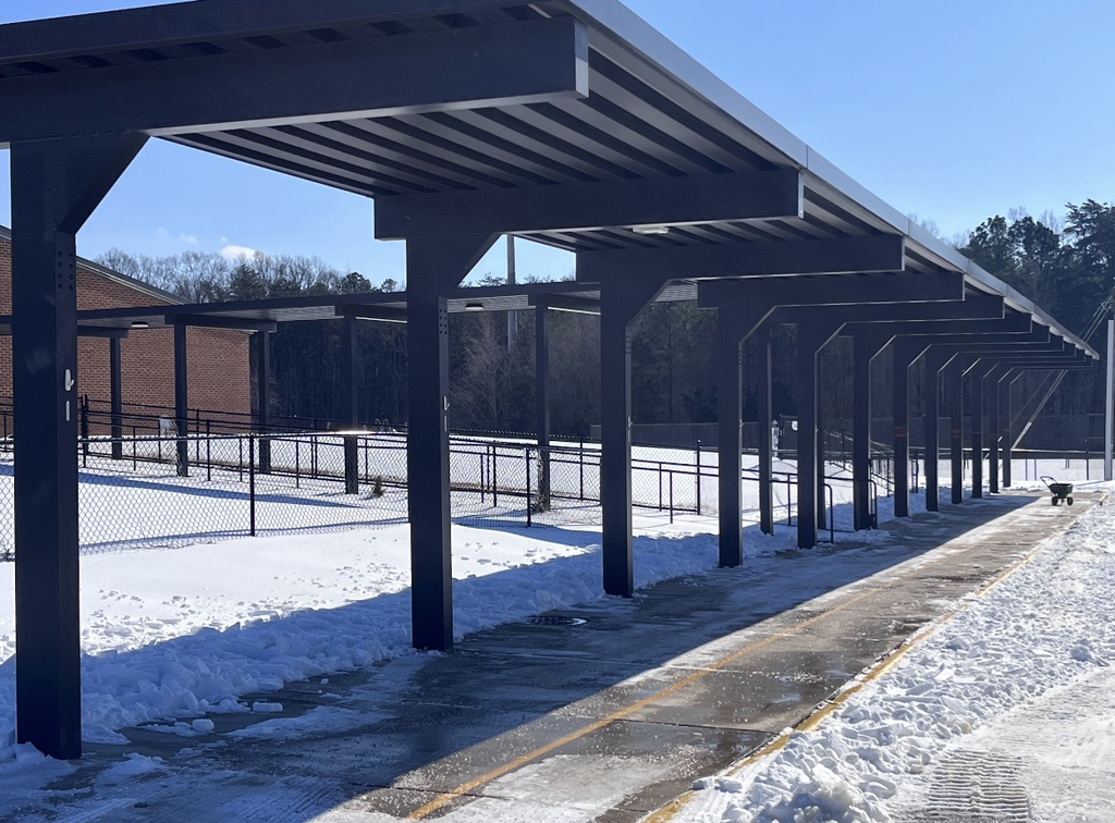 Photo of a school parking lot and sidewalks covered in ice and snow.