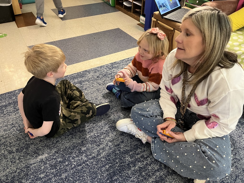 Students use math manipulatives  to learn about the parts of five. A teacher watches.