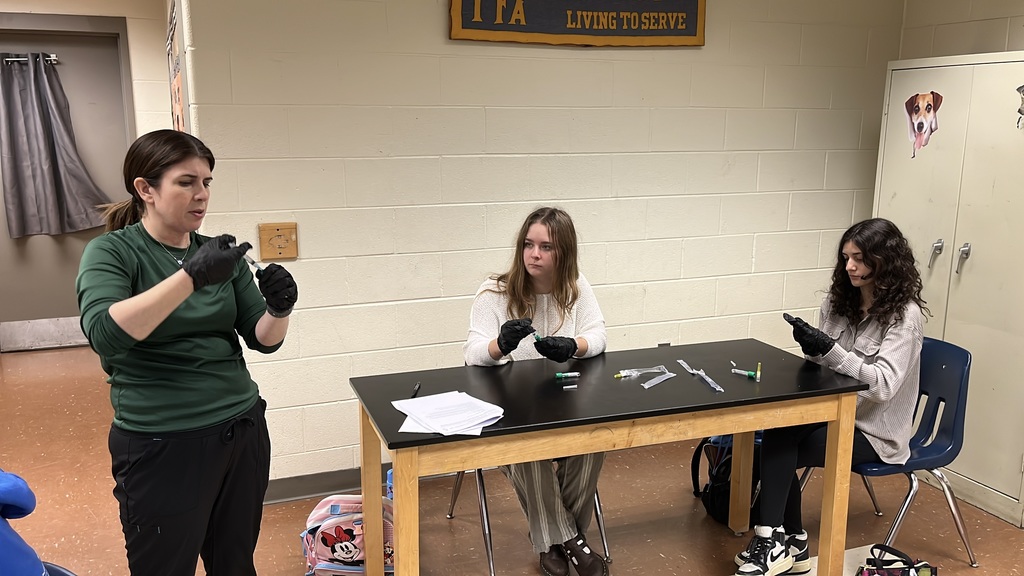 A teacher shows veterinary science students how to mix a vaccine.