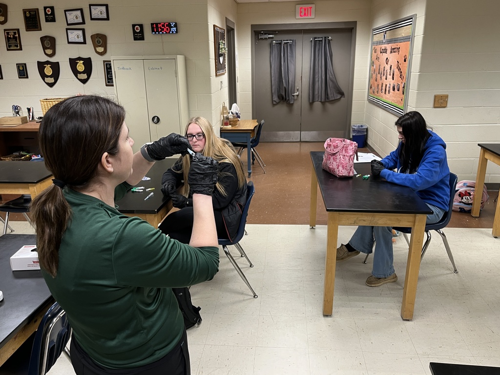 A teacher shows veterinary science students how to mix a vaccine.