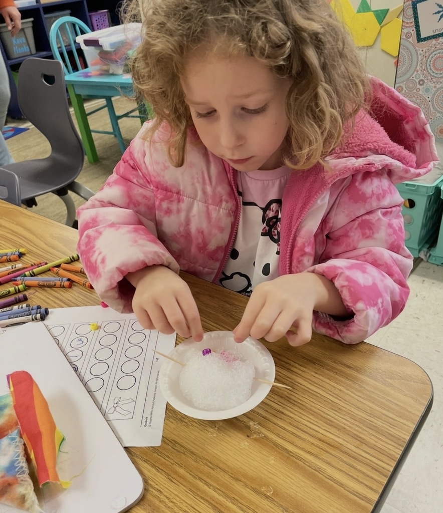 A kindergartener in class makes a personal snowman using crushed ice.