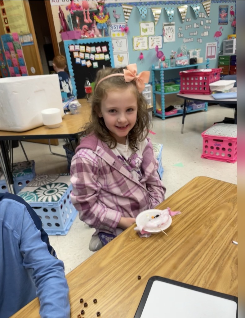 A kindergartener in class makes a personal snowman using crushed ice.