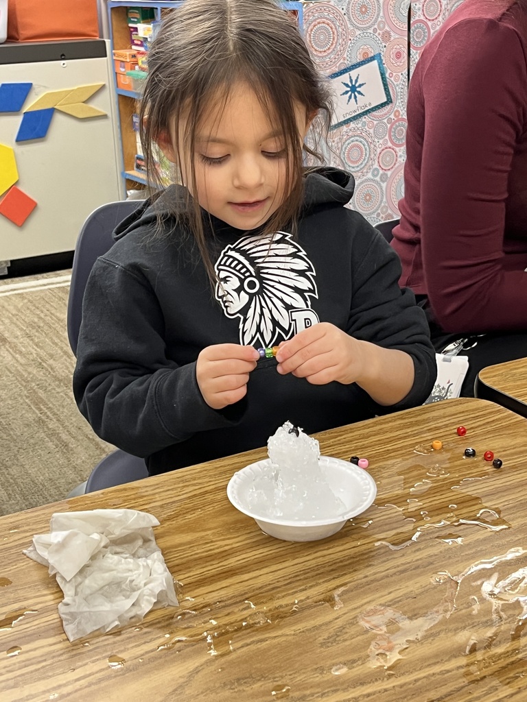 A kindergartener in class makes a personal snowman using crushed ice. 
