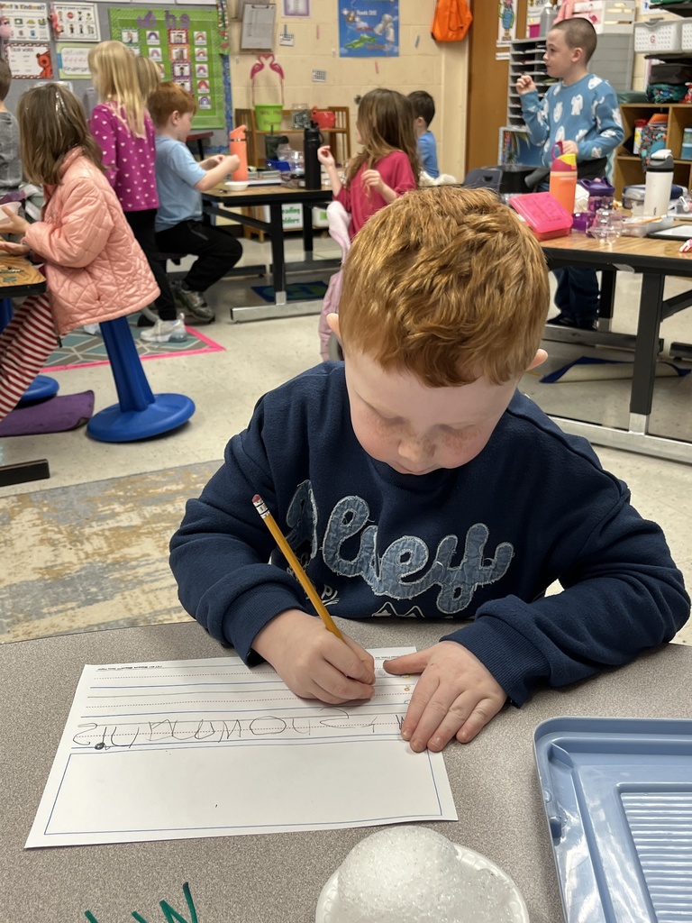 A student writes about a snowman, Behind, kindergarteners in class makes personal snowmen using crushed ice. 
