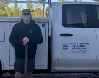 A student poses for a photo in front of a company logo representing where he is doing a Youth Registered Apprenticeship.
