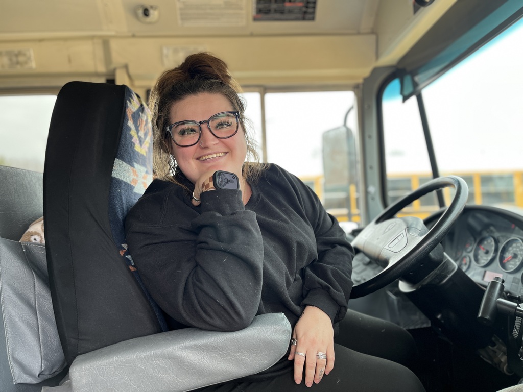 A school bus driver poses for a photo on a school bus.