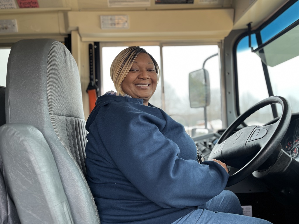 A school bus driver poses for a photo on a school bus.