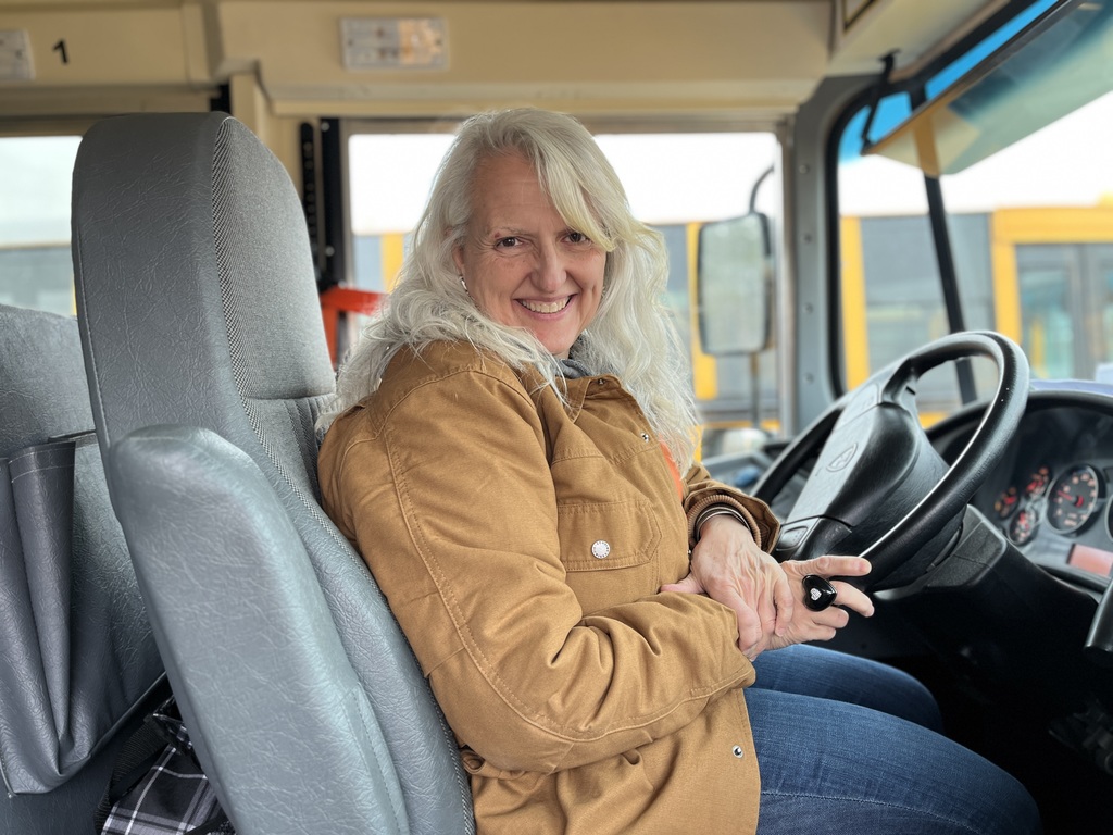 A school bus driver poses for a photo on a school bus.