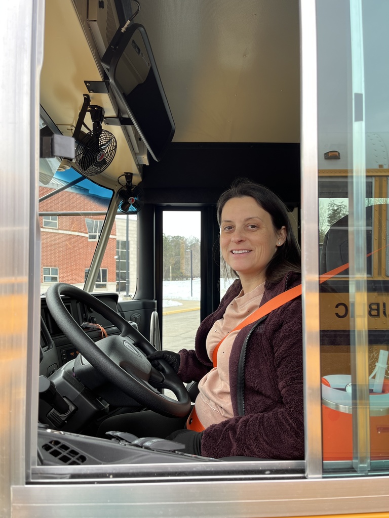 A school bus driver poses for a photo on a school bus.