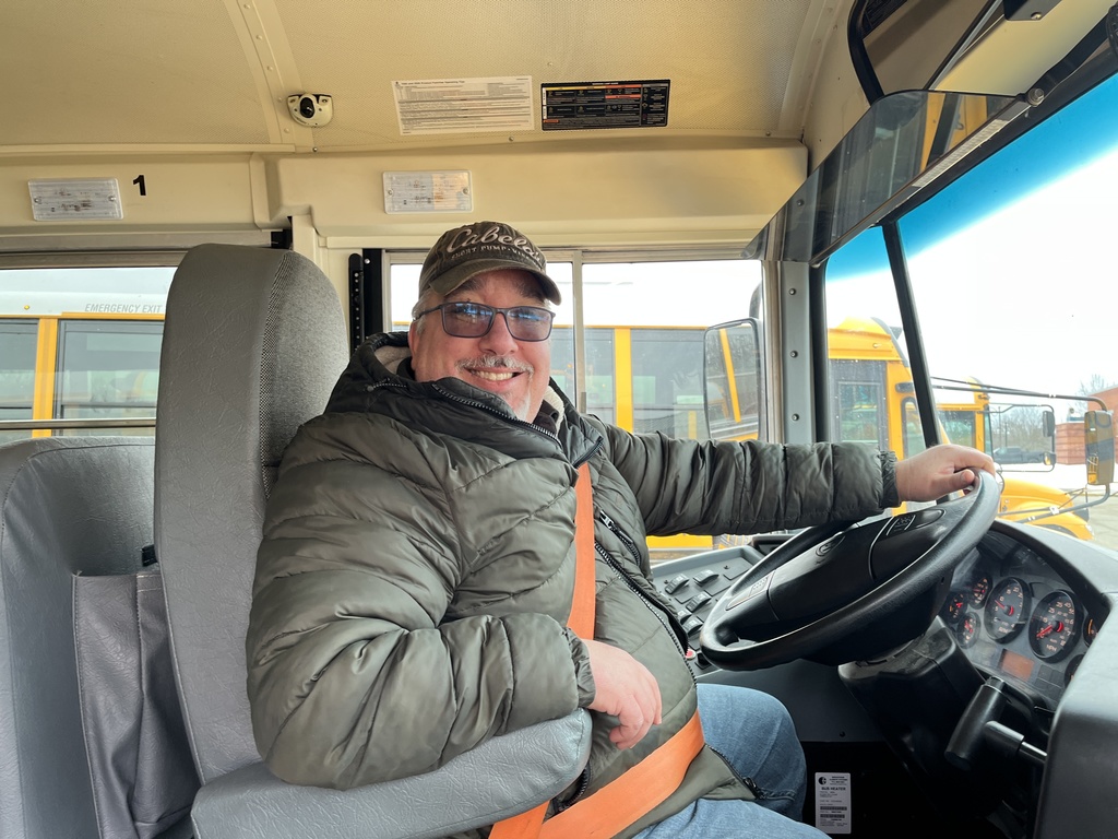 A school bus driver poses for a photo on a school bus.