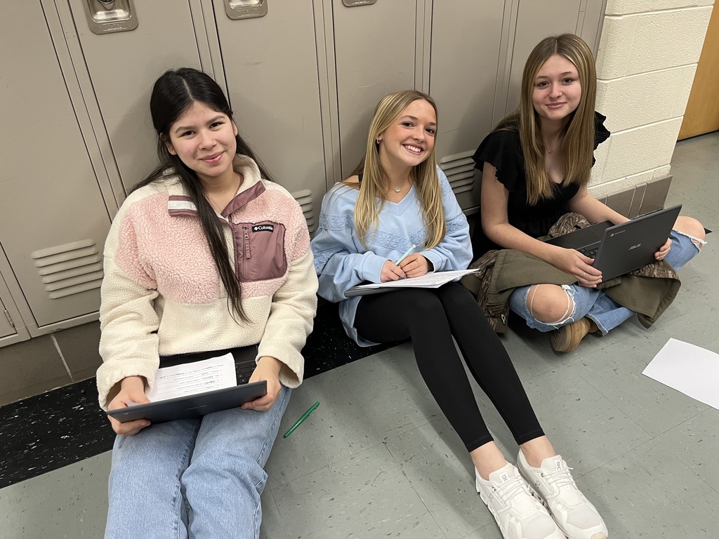 Three students work together in a hallway.