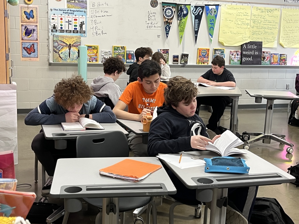 Middle school students look through the book their class is about to study.