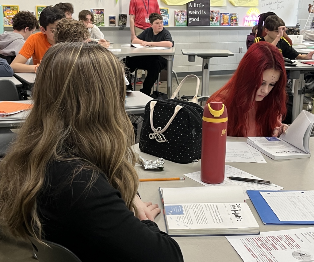 Middle school students look through the book their class is about to study.