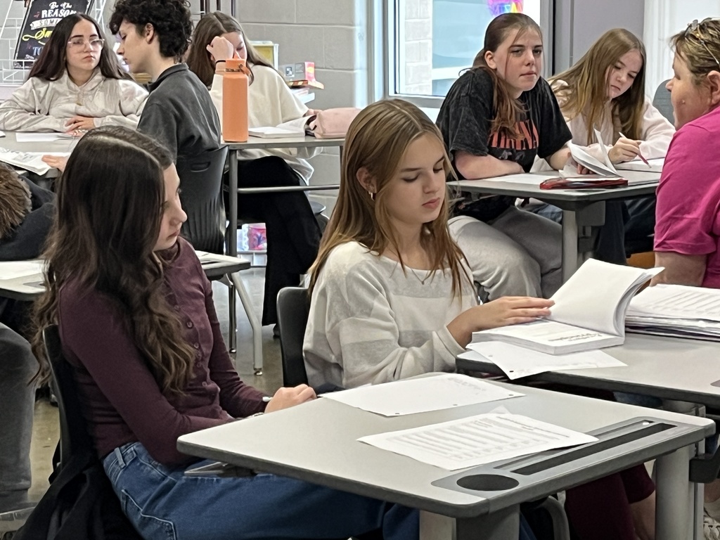 Middle school students look through the book their class is about to study.