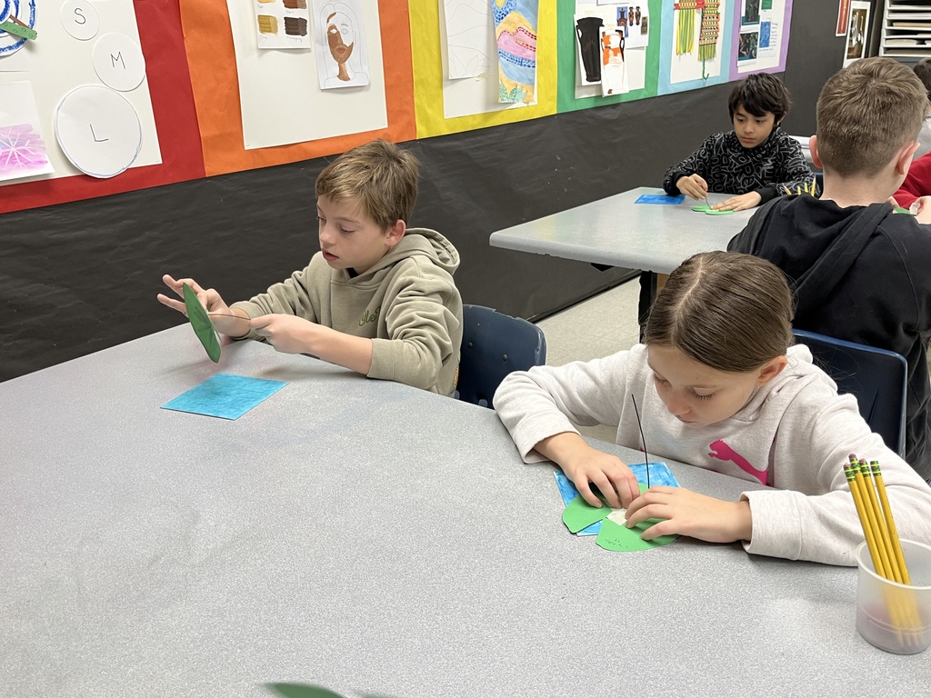 Elementary students in art class bring together the final pieces of their contribution to a koi pond art installation.