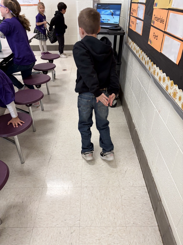 An elementary student assumes the pose of a speed skater after watch the Olympics.