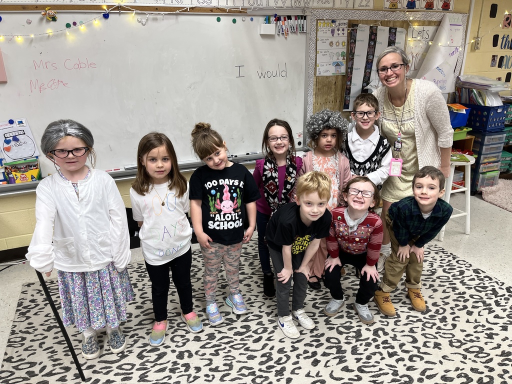 Children  and an adult dressed up for the 100th day of school pose for a photo.