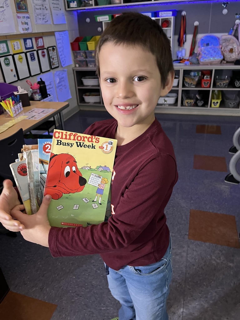 A child show off the books he likes to read during the drop everything and read morning routine.