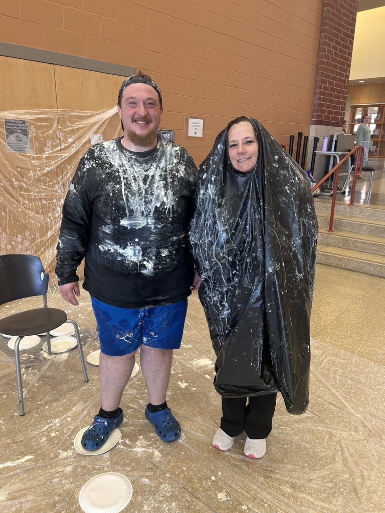 Two adults participate in a pie a teacher fundraiser.