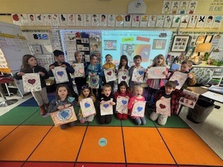 A group of children for a photo holding artwork they created.