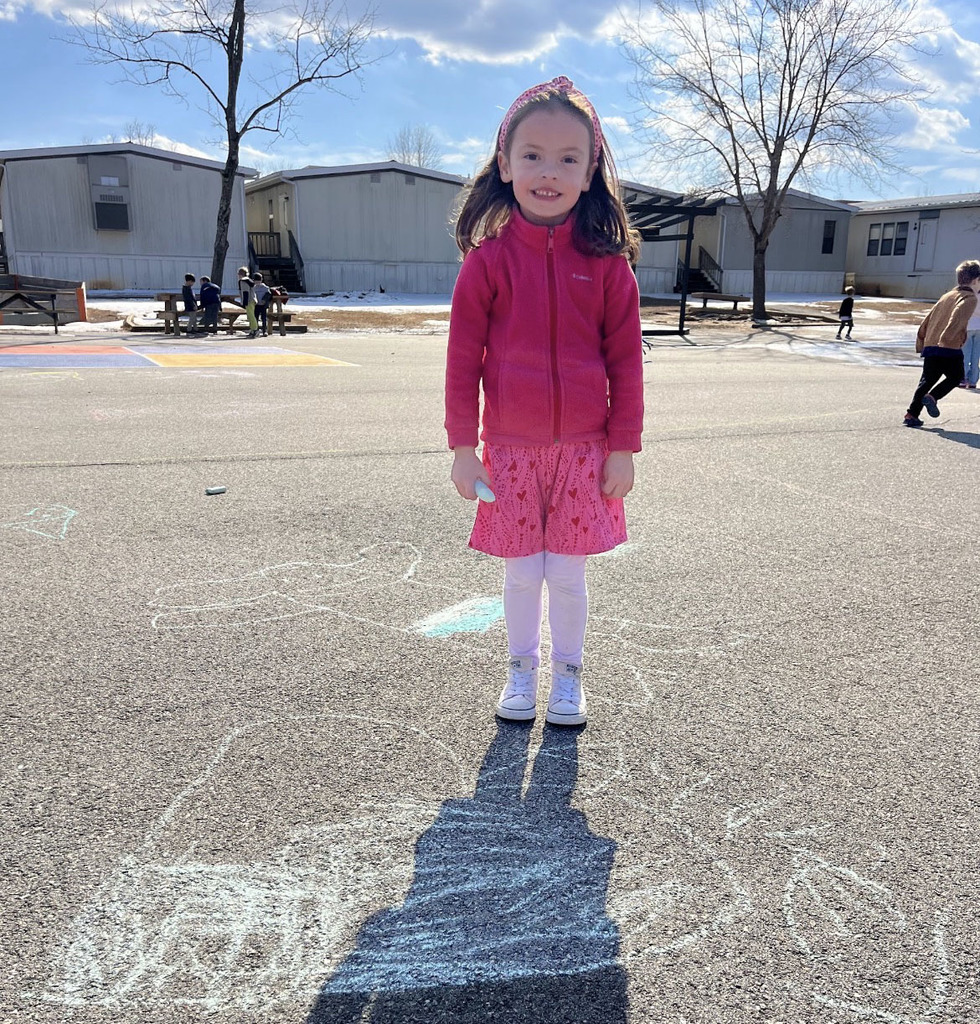 A student poses with chalk art drawn for Kindness Week.
