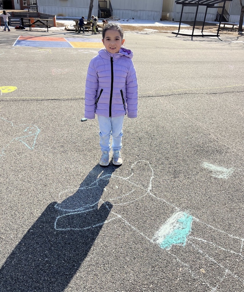 A student poses with chalk art drawn for Kindness Week.
