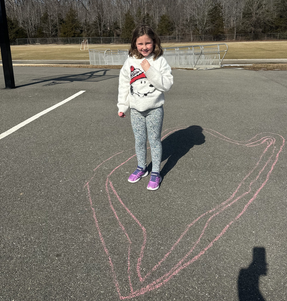 A student stands next to chalk art drawn for Kindness Week.